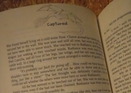 Another page from Heart of Fire, showing a chapter heading framed in a fire-breathing dragon with wings out-spread and tail curled around the words.